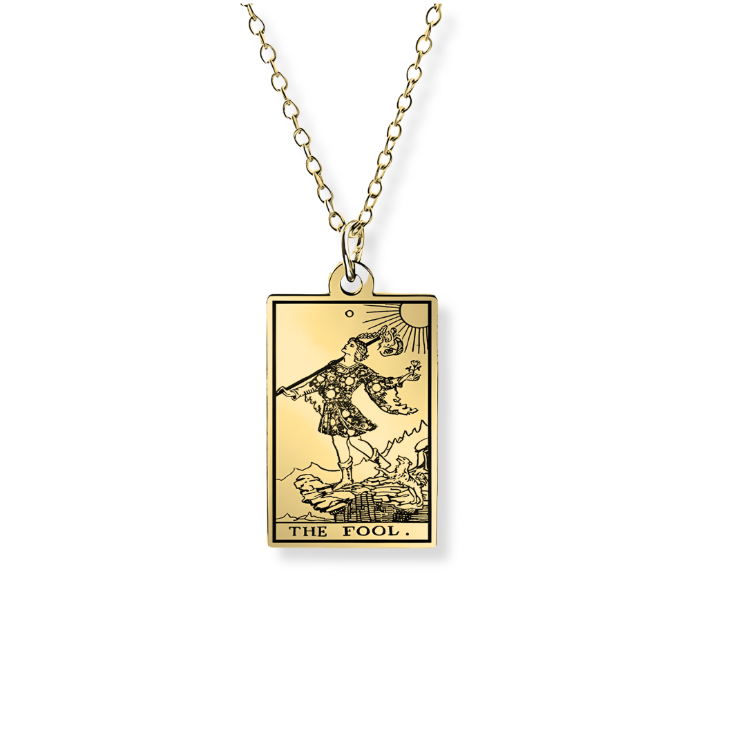 A gold tarot card pendant necklace featuring 'The Fool' card, suspended from a delicate rose gold chain against a clean white background.