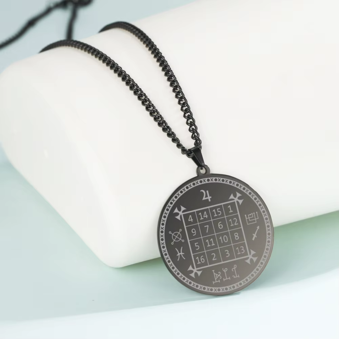 A round black pendant necklace featuring an engraved magic square grid and symbols, hanging from a black beaded chain on a white display stand.