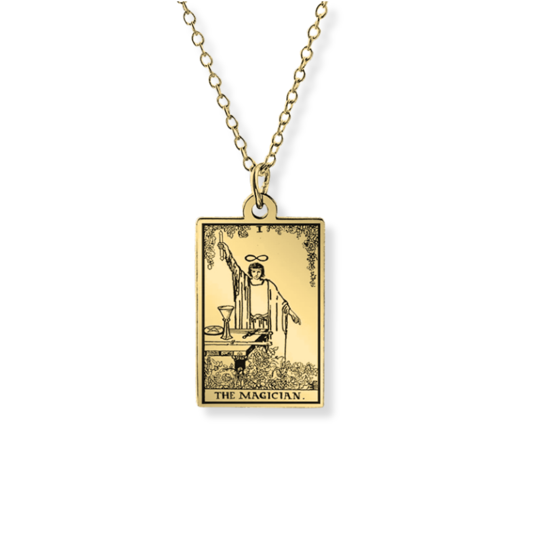 A gold-toned tarot card pendant necklace featuring 'The Magician' card design on a rectangular pendant, suspended from a matching chain against a plain white background.