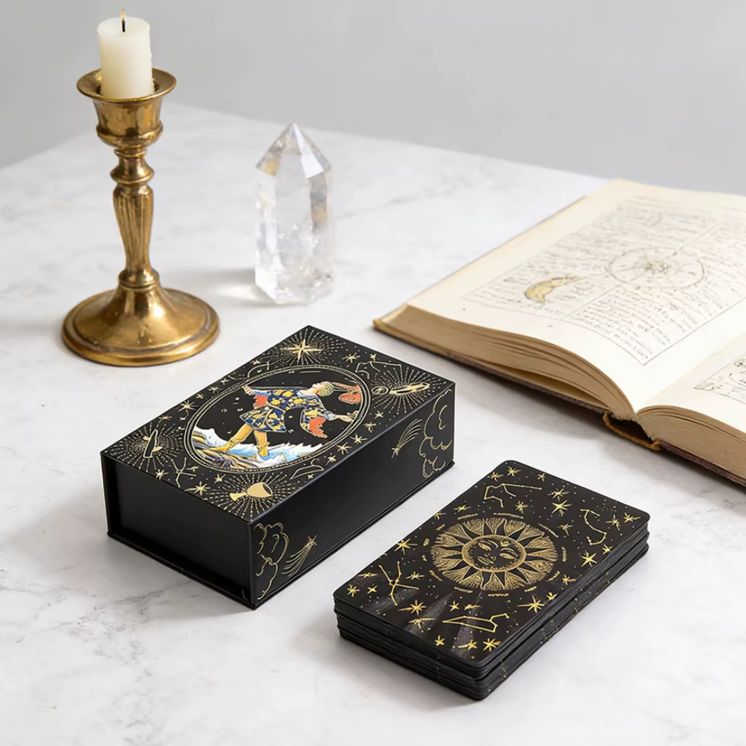 Black decorative box with celestial design, matching cards, candle, and crystal on a white surface