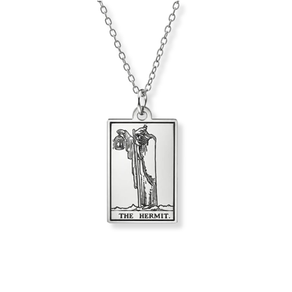 A silver-toned pendant necklace featuring a rectangular card design with the Hermit card illustration and the text 'THE HERMIT' at the bottom, shown on a white background.