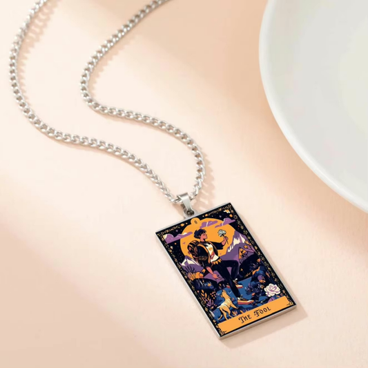 Necklace with a tarot card pendant on a beige surface
