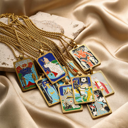 Set of tarot card-themed pendants on gold chains against a beige fabric background