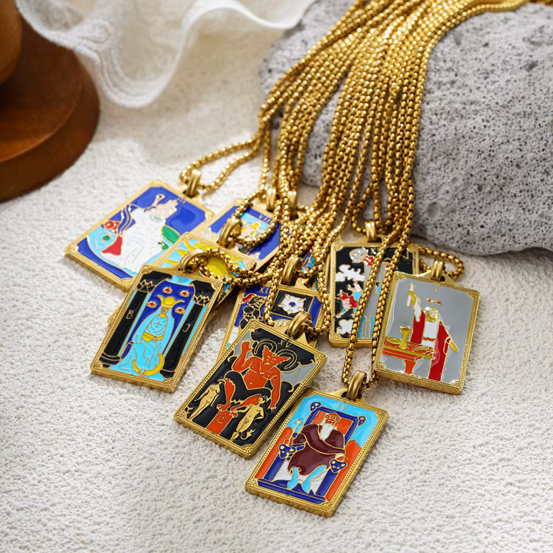 Collection of tarot card-themed pendants on gold chains against a rock background