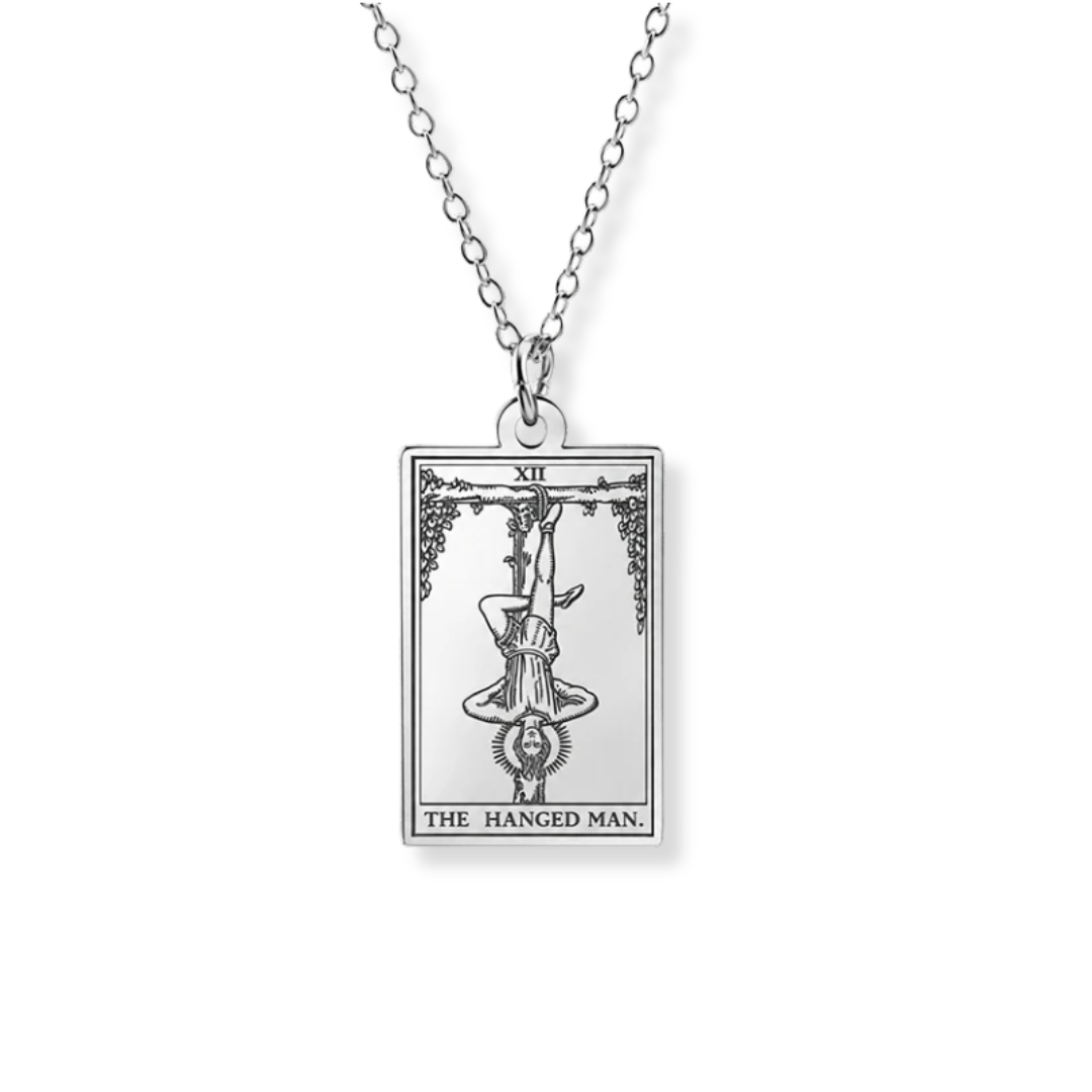 A silver-toned tarot card pendant necklace featuring 'The Hanged Man' card design, suspended from a delicate link chain against a plain white background.