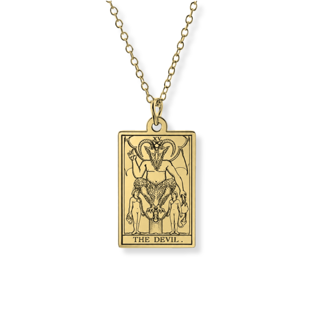 A gold-toned tarot card pendant necklace featuring 'The Devil' card artwork, suspended from a matching chain against a plain white background.