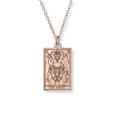 A rose gold tarot card pendant necklace featuring 'The Devil' card design, suspended from a matching rose gold chain against a plain white background.