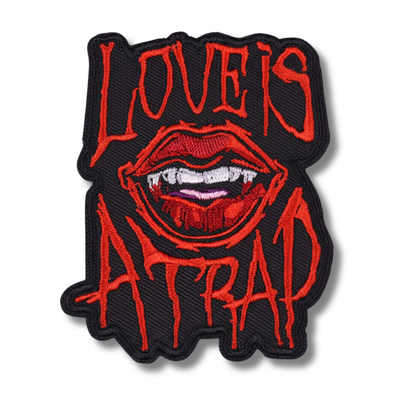Embroidered patch with red lips and text 'LOVE IS ATTRACTION' on a white background