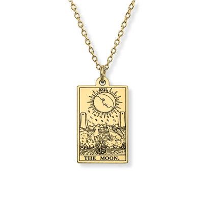 A gold-toned necklace featuring a rectangular pendant engraved with the 'The Moon' tarot card design, suspended from a matching chain against a plain white background.