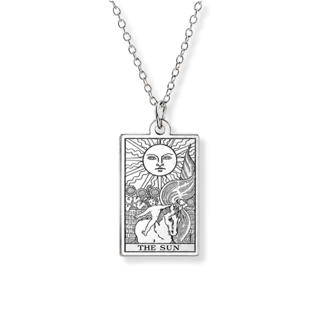A silver-toned necklace featuring a rectangular pendant with an engraved tarot card design titled 'THE SUN,' shown on a plain white background.