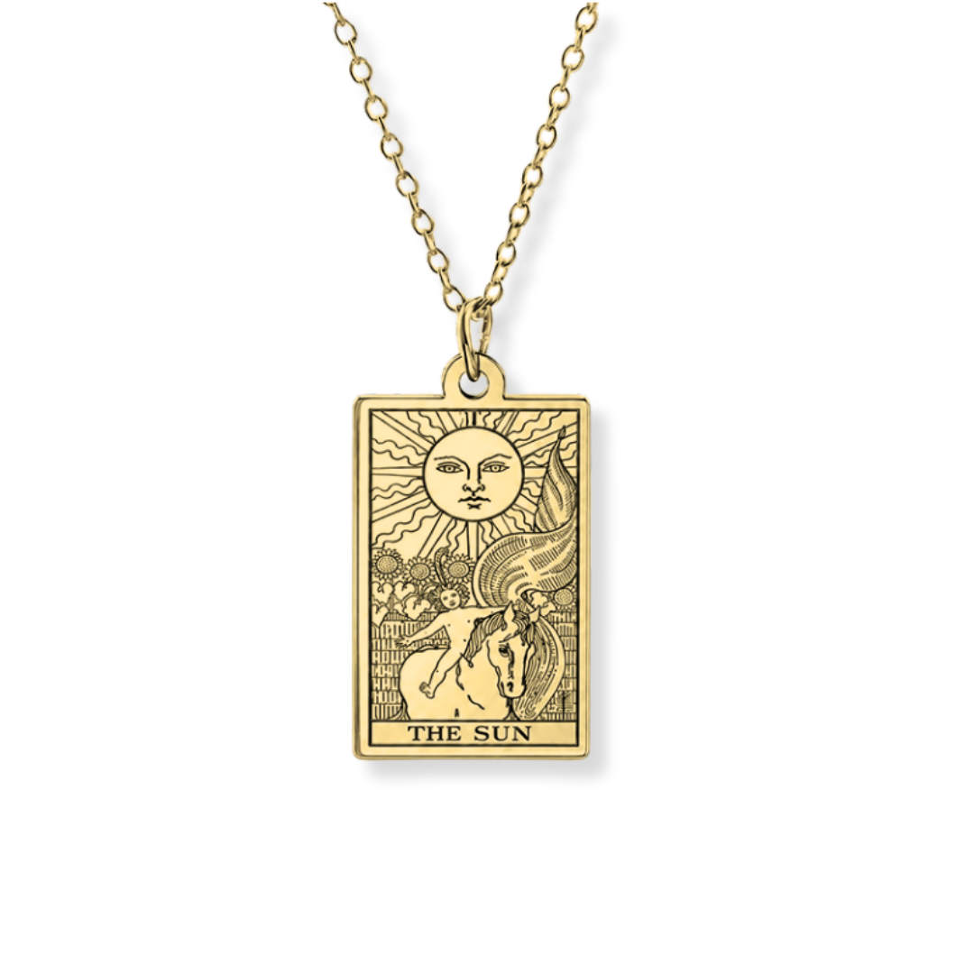 A gold-toned tarot card necklace featuring 'The Sun' card engraved on a rectangular pendant, suspended from a matching chain against a plain white background.