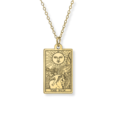 A gold-toned tarot card necklace featuring 'The Sun' card engraved on a rectangular pendant, suspended from a matching chain against a plain white background.