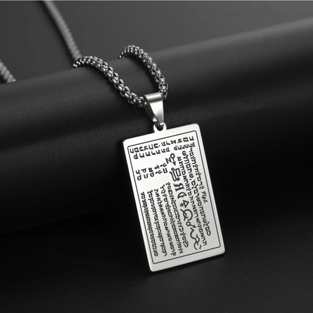 A silver rectangular pendant necklace with engraved script and symbols from the 6th & 7th Books of Moses, hanging from a silver chain against a dark textured background.