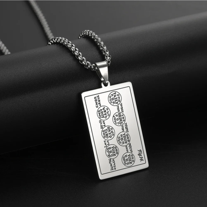 A silver rectangular pendant necklace with engraved script and symbols from the 6th & 7th Books of Moses, hanging from a silver chain against a dark textured background.