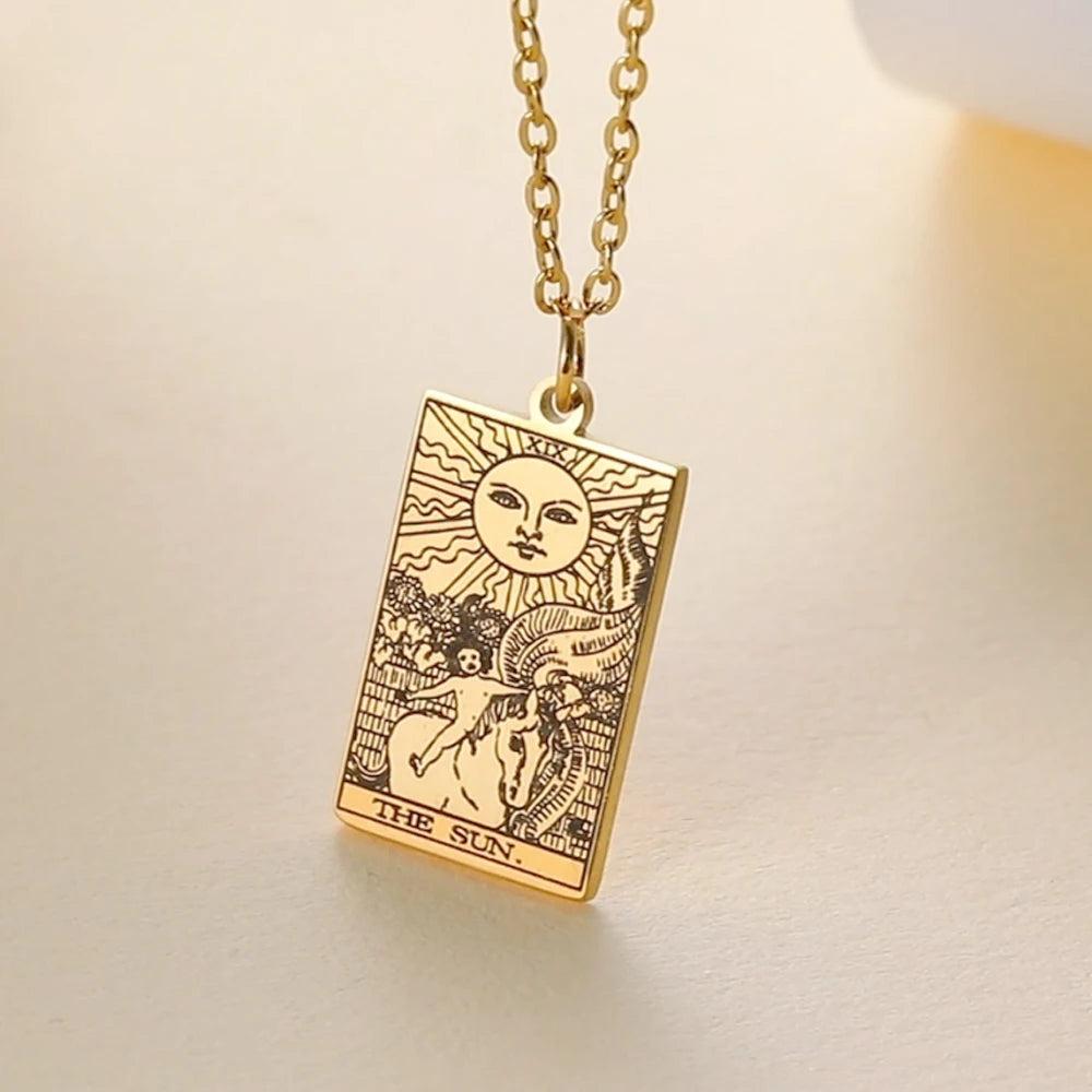 Gold necklace with a 'The Sun' tarot card pendant on a beige background