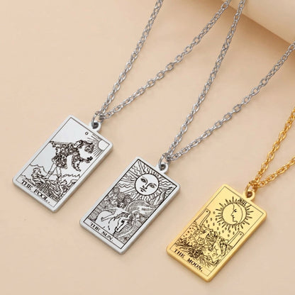 Three tarot card pendants on chains against a teal background