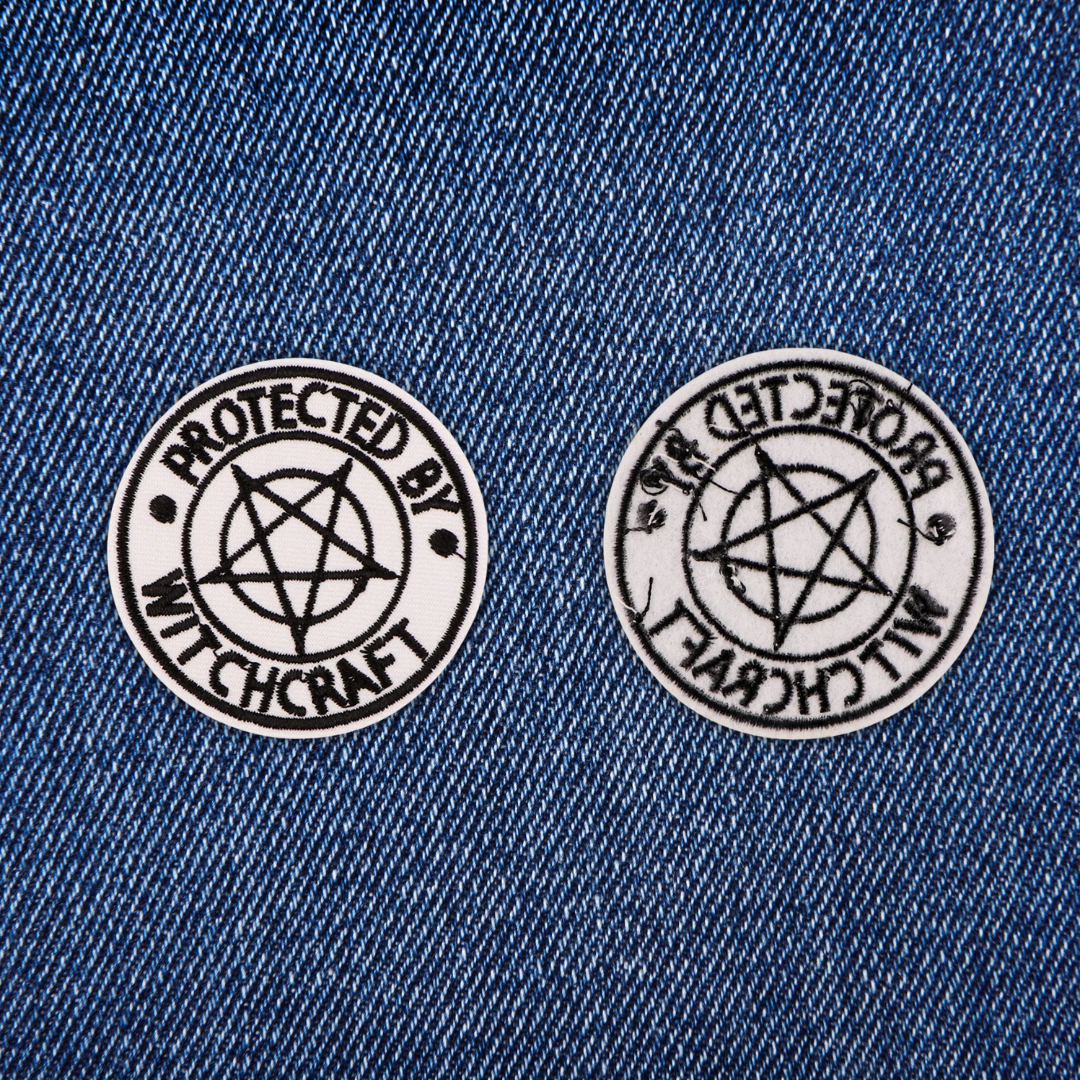 Two 'Protected by Witchcraft' patches on a denim background